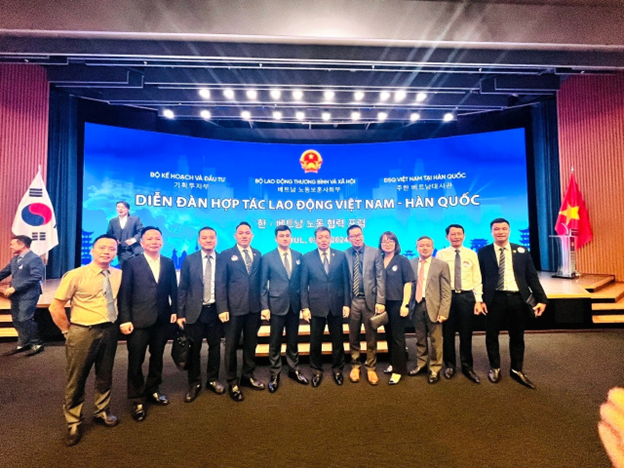 A group of people standing in front of a large screenDescription automatically generated